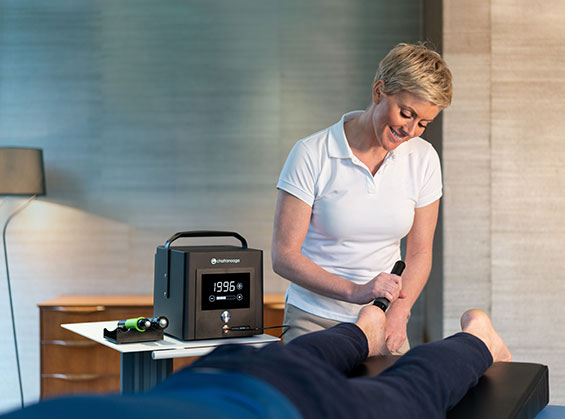 圧力波（拡散型衝撃波）施術器Chattanooga®︎ INTELECT RPW LITEを使用して足底腱膜炎の施術をおこなっている女性の写真