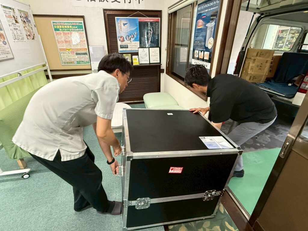 玄関の段差を越えるため、大分ごとう整骨院院長と酒井医療のスタッフさんの2人がかりで、パワーマグを慎重に運び入れているところ。