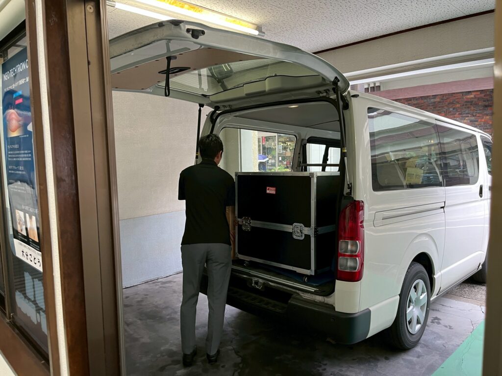大分ごとう整骨院の駐車場にて、ハイエースの荷台からパワーマグを慎重に降ろしているところ