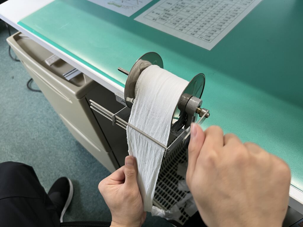 包帯巻き器で巻軸包帯を作っている様子