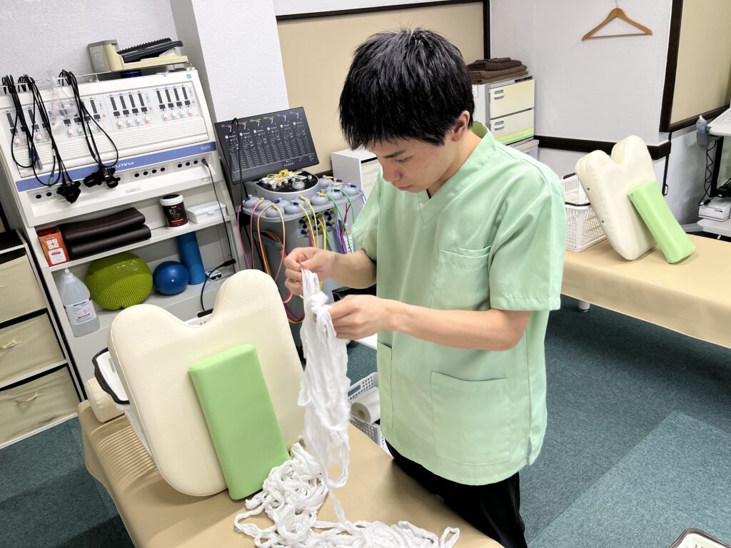 洗濯後の包帯をほぐす大分ごとう整骨院の柔道整復師　藤澤琉人先生